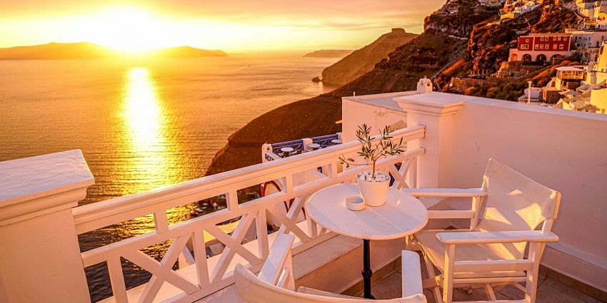 Dinner place in Santorini with two chairs, a table and a sunset view of the city.