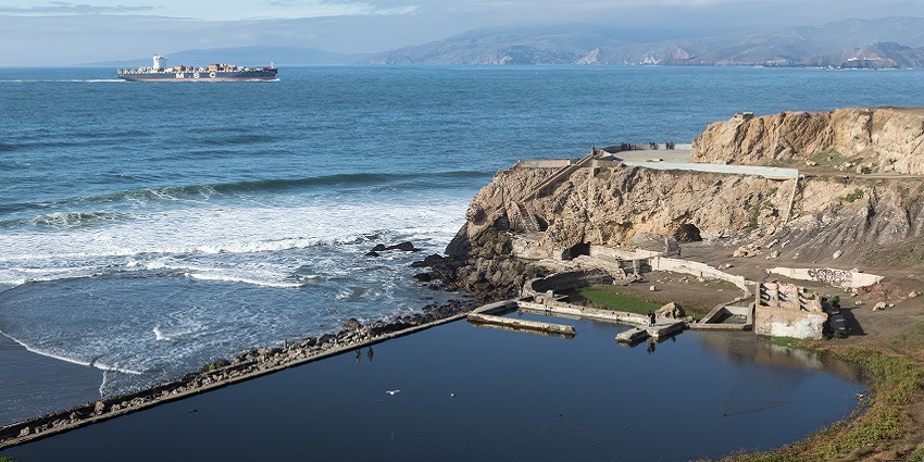 A distant view of the Sutro Baths, which is showcased being separated from a water body.