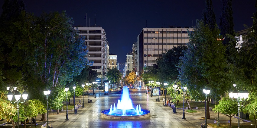 Syntagma Square Park at night with people sitting on the benches and a water fountain