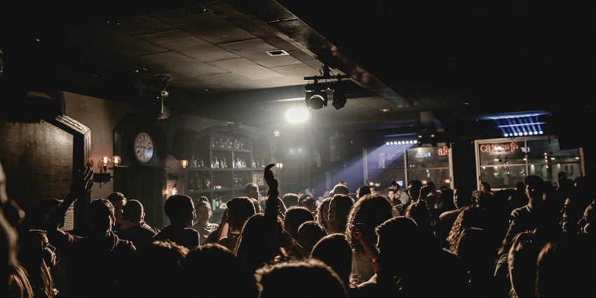 A crowd of people dancing and raising their hands while dancing in unique lighting
