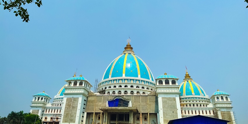 A photo of the front view of a large Hindu temple with a colourful and intricate facade.