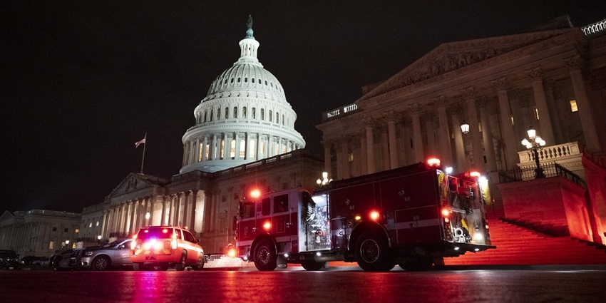 Outside of the United States Capitol Building at night time and a few moving vehicles