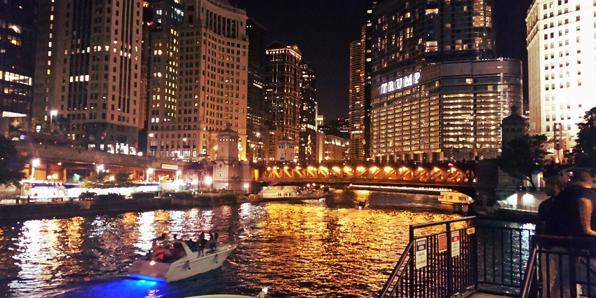 A nighttime view of the Chicago River in front of the city’s well-lit and tall skylines