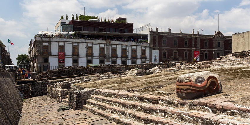 A view of Temple Mayor showcasing the stone-carved stairs surrounded by buildings.