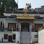 A view of Geden Tharpa Choling Monastery, featuring traditional Buddhist architecture.