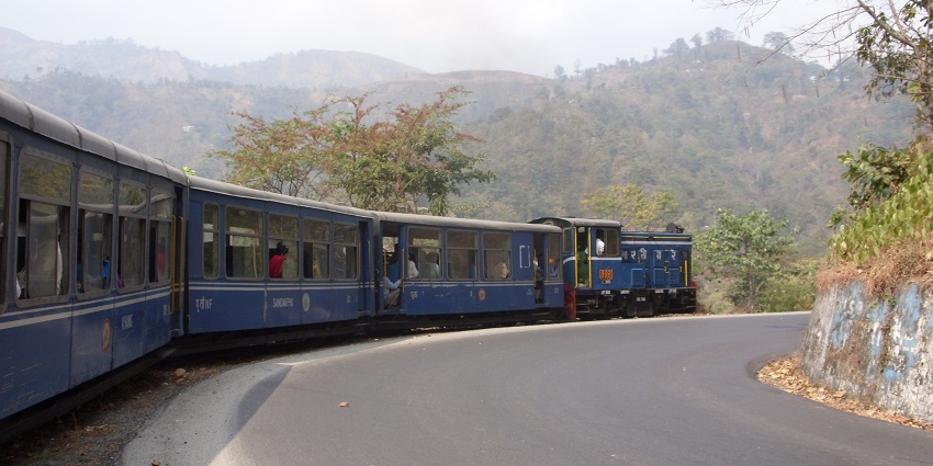 A picture of a train arriving at the railway station along with many people waiting to board.