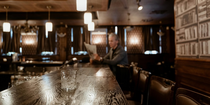 A clear glass on the bar counter table where you can enjoy vibrant Romania nightlife.