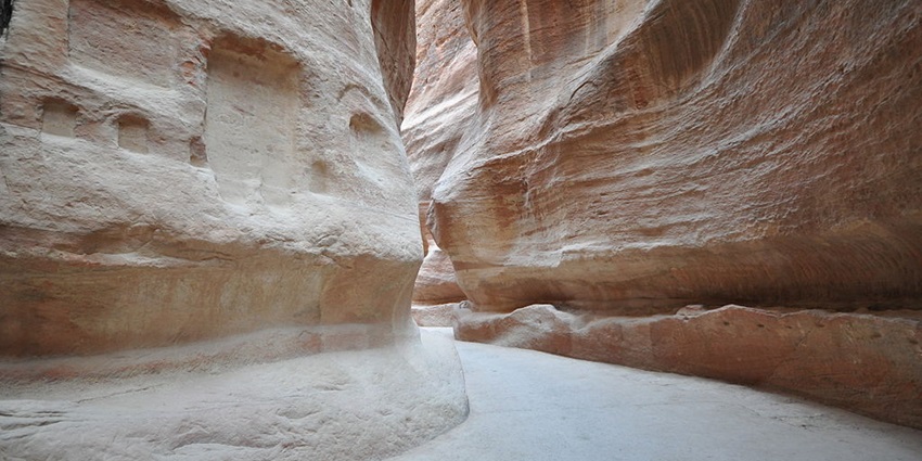 An image of Al-Siq, a narrow, winding gorge leading to Petra's iconic monuments.