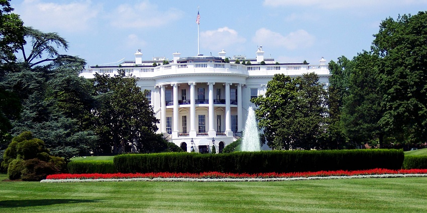 A fountain is present, surrounded by greenery across which there is the White House.