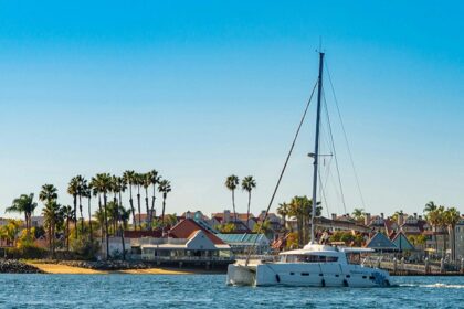 A panoramic view of a yacht near the coast with homestays in the background.