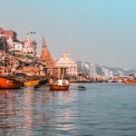 A picture of Prabhu Ghat in Varanasi, India, from the Ganga River, dotted with boats.