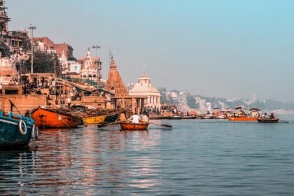 A picture of Prabhu Ghat in Varanasi, India, from the Ganga River, dotted with boats.