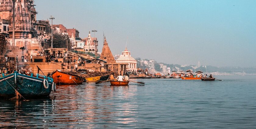 A picture of Prabhu Ghat in Varanasi, India, from the Ganga River, dotted with boats.