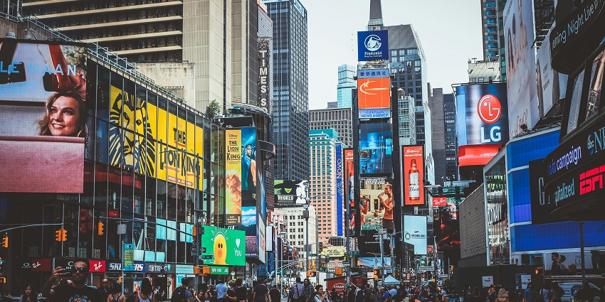 Times Square is filled with people and advertisements and is surrounded by tall buildings.