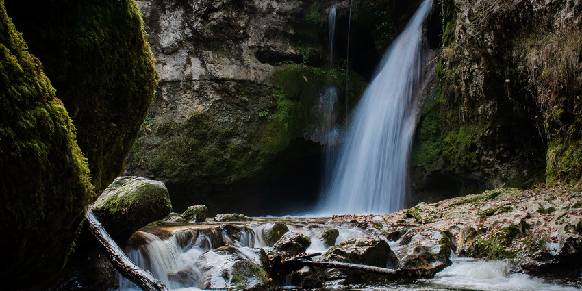 Unique waterfall nestled in a gorge with lush greenery.