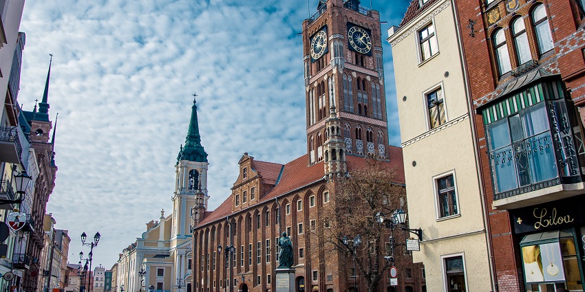 Old town hall in Torun with old-style architected buildings, people walking and exploring