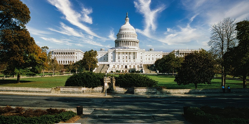A distant view of the Capitol building is showcased with a few people at the entrance.