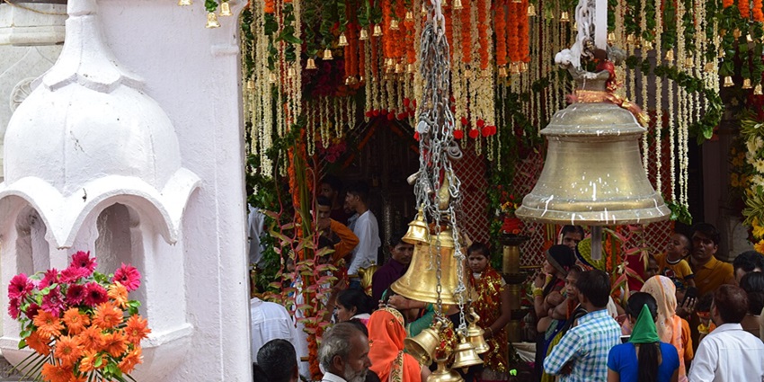 Vajreshwari Temple front view with devotees and bells around.