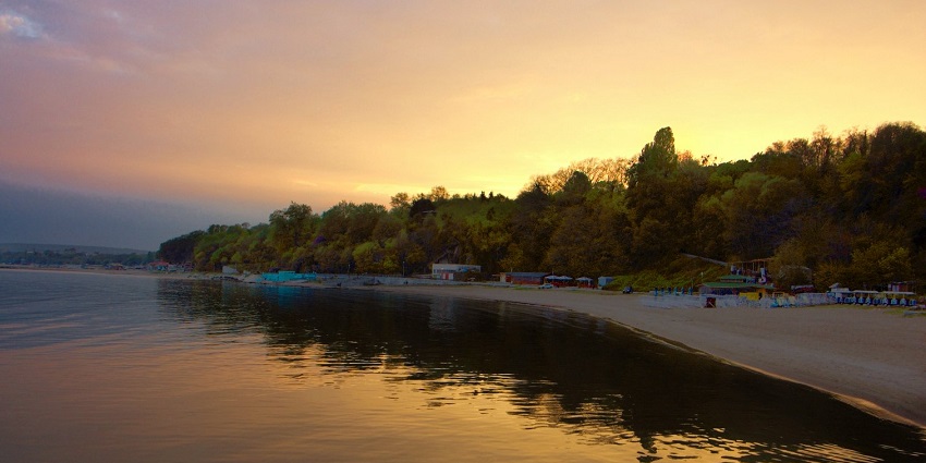 Sunset at Varna beach with a sandy shoreline and tourist places surrounded by greenery