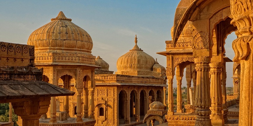 An image of a temple building with a dome and arches, illuminated during golden hour.