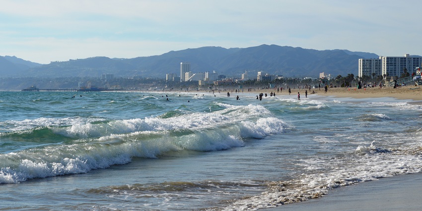 An image of Venice Beach, Los Angeles, showcasing palm trees, a lively boardwalk, and the ocean.