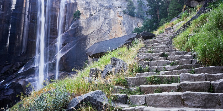 An image of Vernal Falls viewed from the Mist Trail, with water cascading over rock.
