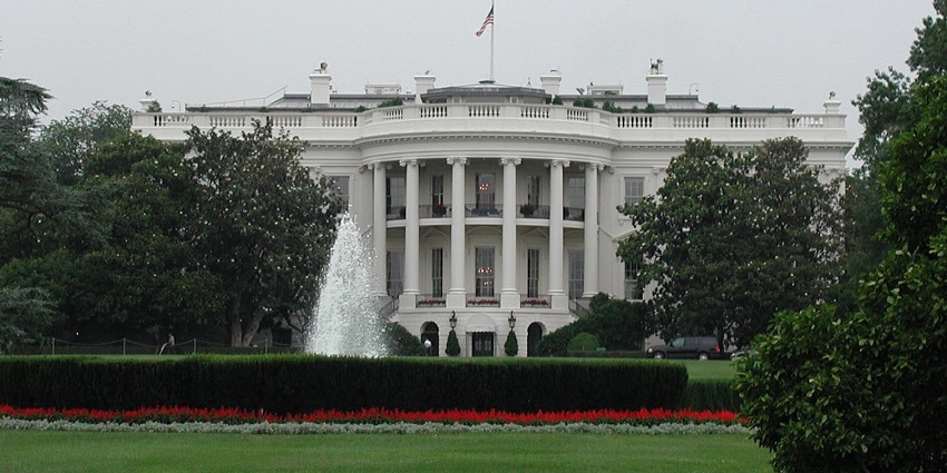 A fountain is present, surrounded by greenery across which there is the White House