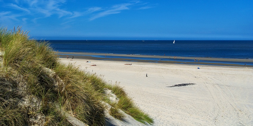 Image of calm and quiet island beach with clear waters, and dunes