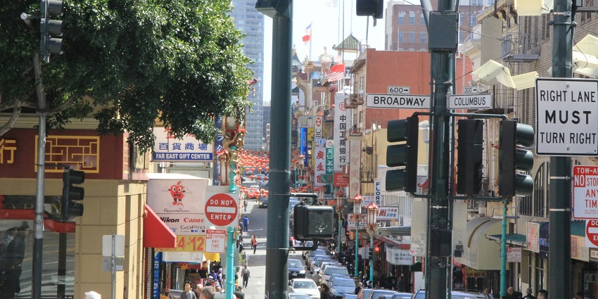 A vibrant street with various sign boards in Chinese language and many vehicles passing by