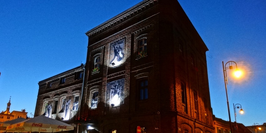 Podwale Street in the evening with a well-lit jazz club building and street lamp lights