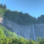 A serene view of Hickory Nut Falls in North Carolina, with the waterfall surrounded by green foliage.