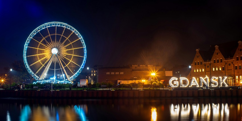 Waterfront Gdansk with a lit Gdansk signage beside Motława river and Ferris wheel