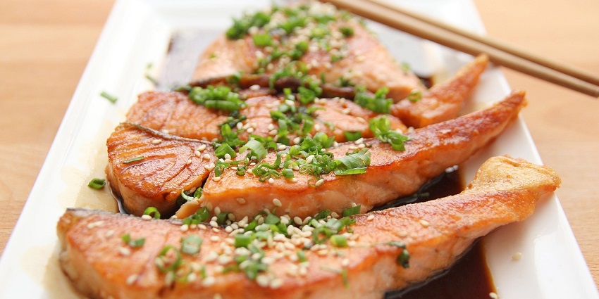 Delicious plate of teriyaki salmon with garnishes, served as a gourmet meal.