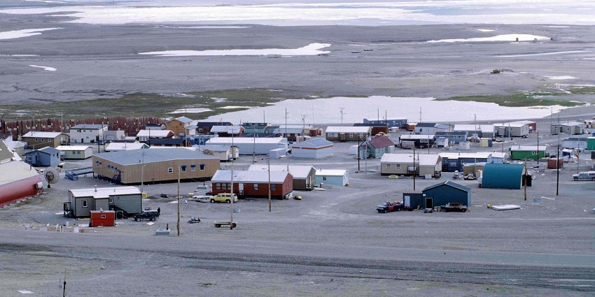 A panoramic view of Resolute Bay with uneven terrain, scattered rocks, and sparse vegetation.