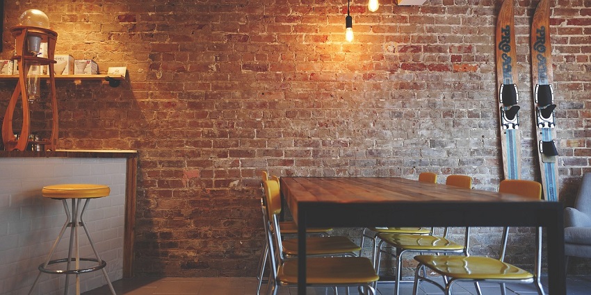 An image of a seating area with modern chairs and a table against a rustic brick wall background