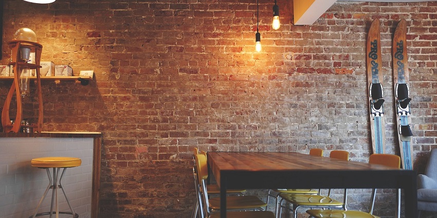 A seating area with modern chairs and a table against a rustic brick wall background