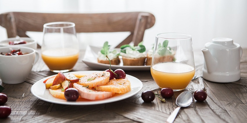 A refreshing breakfast drink served with a colorful assortment of fruit on the side