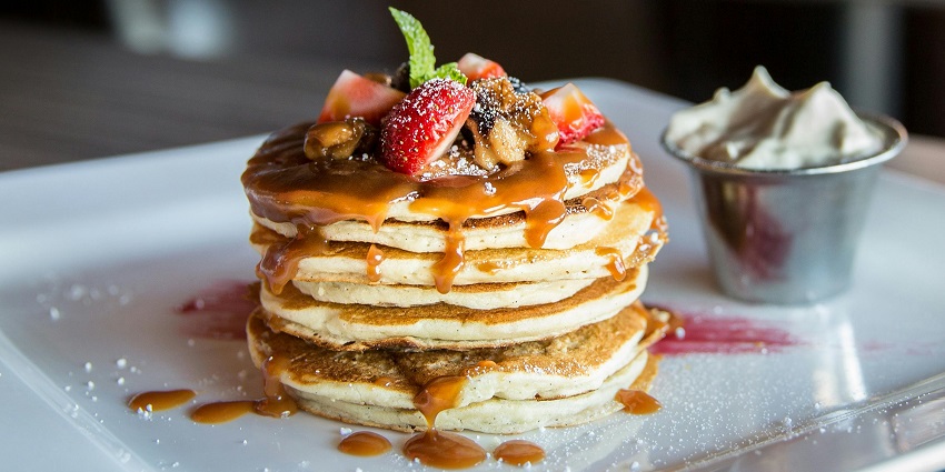 Image of delectable pancakes with chocolate syrup and strawberries on top