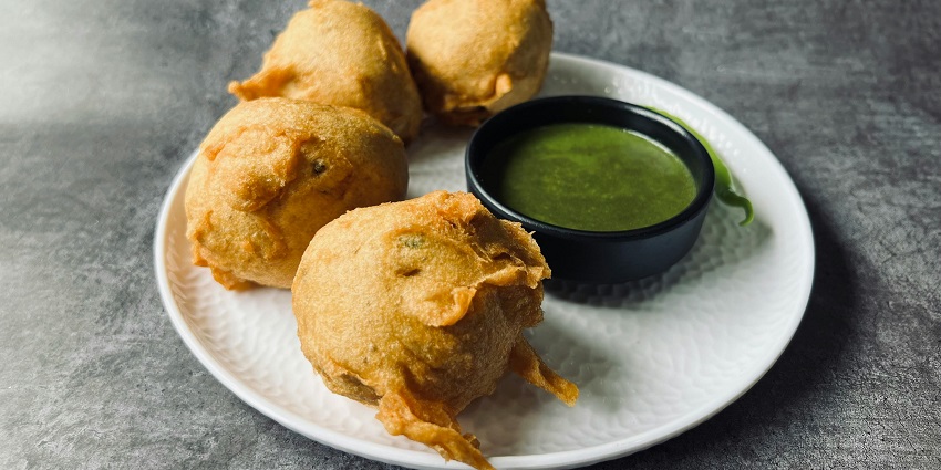 Image of delectable pakoda/vada served on a plate with green chutney on the side