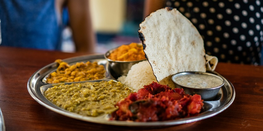 Image of a food thali with rice and different curries on the side and a flatbread