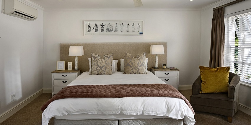 Modern bedroom with large windows, cosy bedding, and stylish decor in natural lighting.