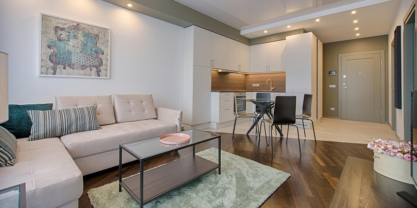 An image of a modern living room with stylish furniture, bright decor, and large windows letting in natural light.