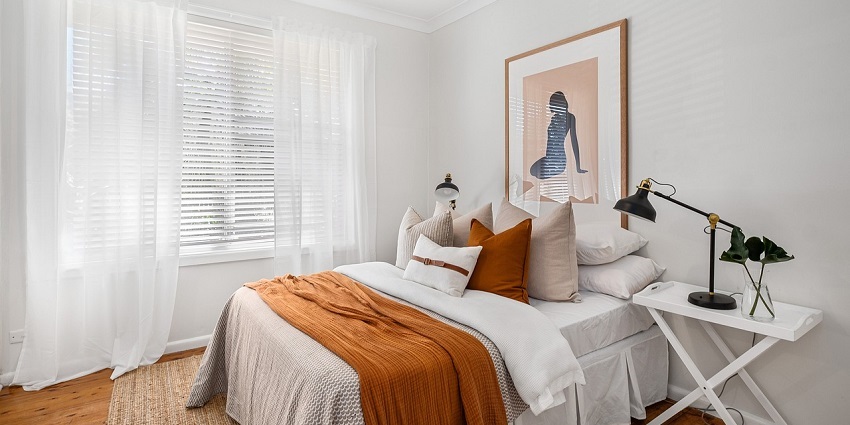 Modern bedroom with large windows, cosy bedding, and stylish decor in natural lighting