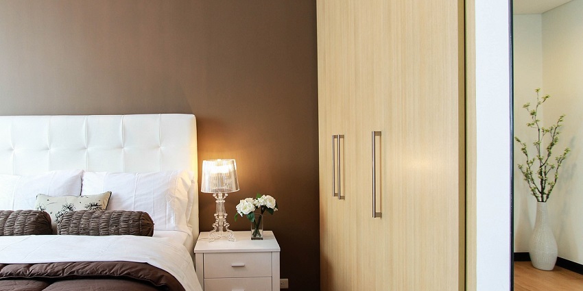 A spacious bedroom with a cosy bed, open closet, and soft lighting for a relaxing atmosphere.
