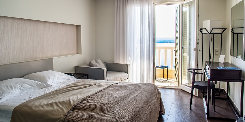 An image of a well-appointed hotel room with a comfortable bed, a seating area, and a balcony