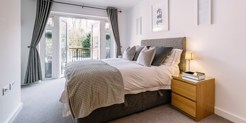 A view of an elegant bedroom with a large bed, decorative pillows, and soft lighting