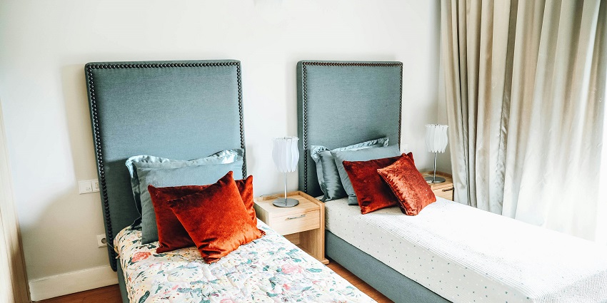 An image of a hotel room with two beds and decorated room with beautiful lamp in the middle