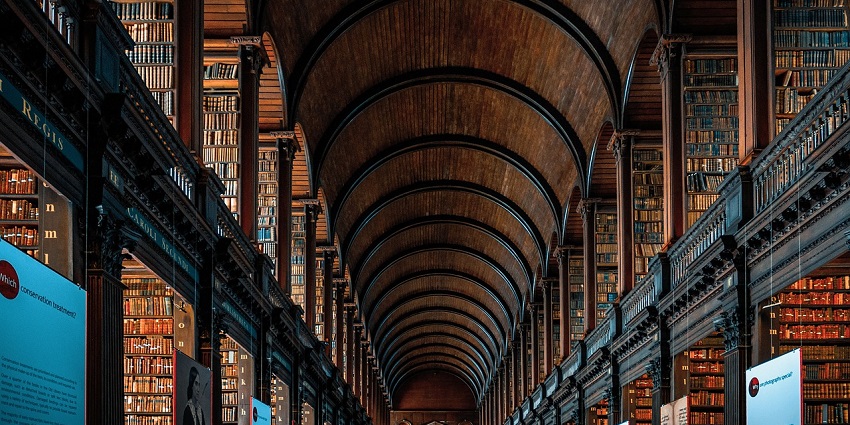 Library with tall bookshelves filled with various books, creating a cosy, quiet atmosphere.