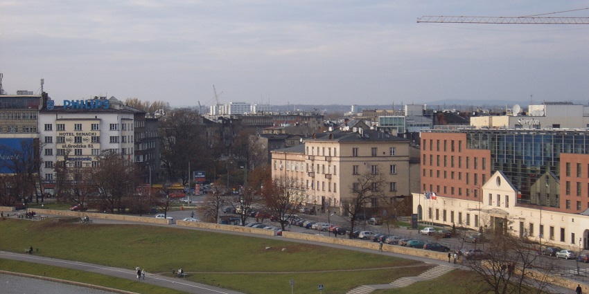 Wisla river bank with a park beside the river, people walking on sidewalks and buildings