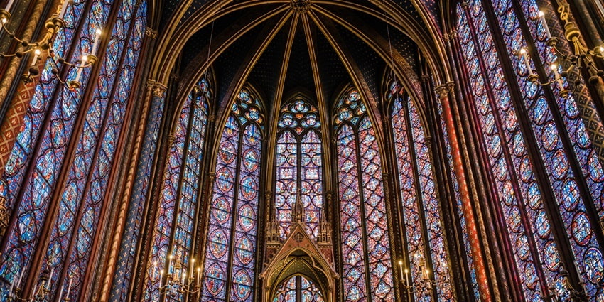 A picture of the interiors of a church in Paris with majestic decorations on its tall walls